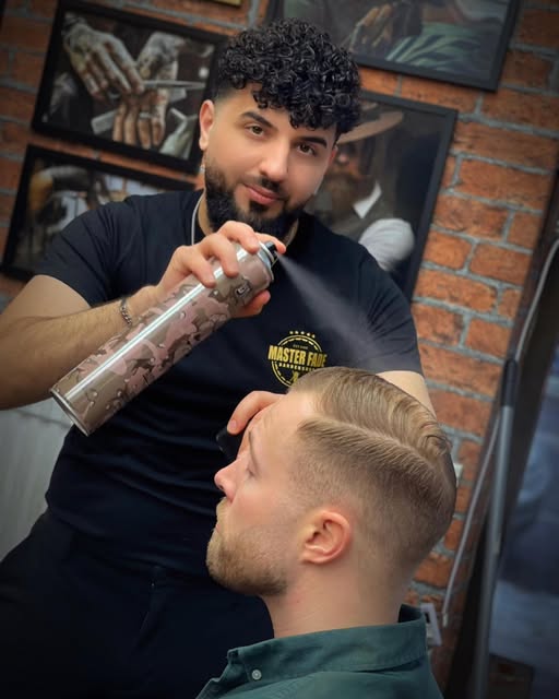Barberare avslutar en klippning med spray i salongen